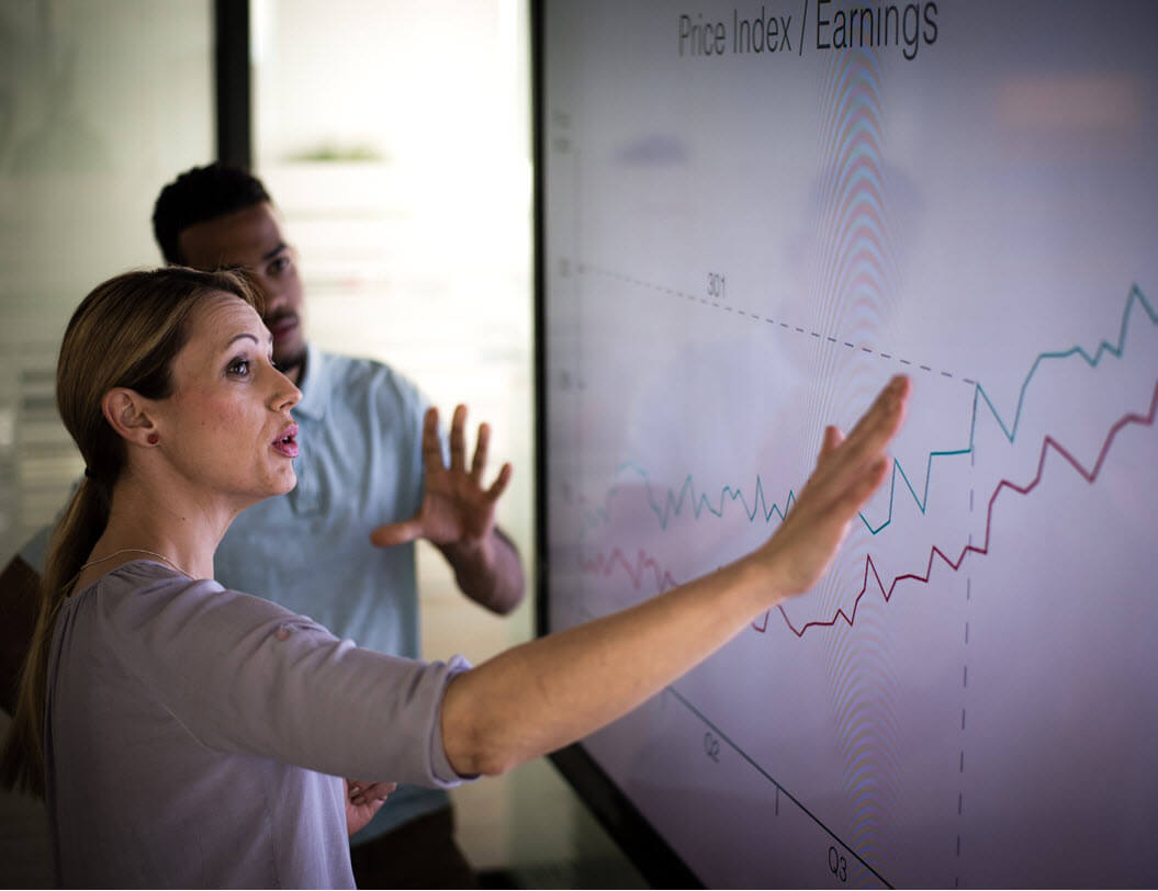 Professional man and woman looking at data on large screen