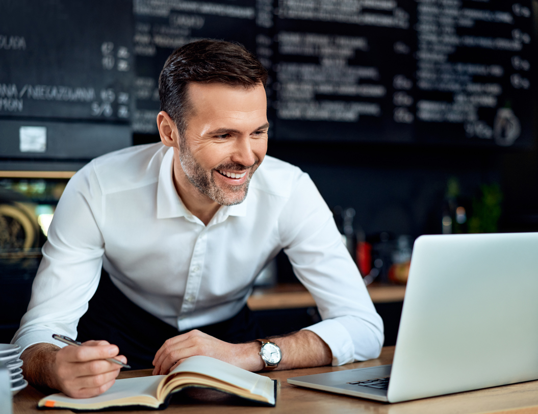 Male business owner using laptop, managing expenses.