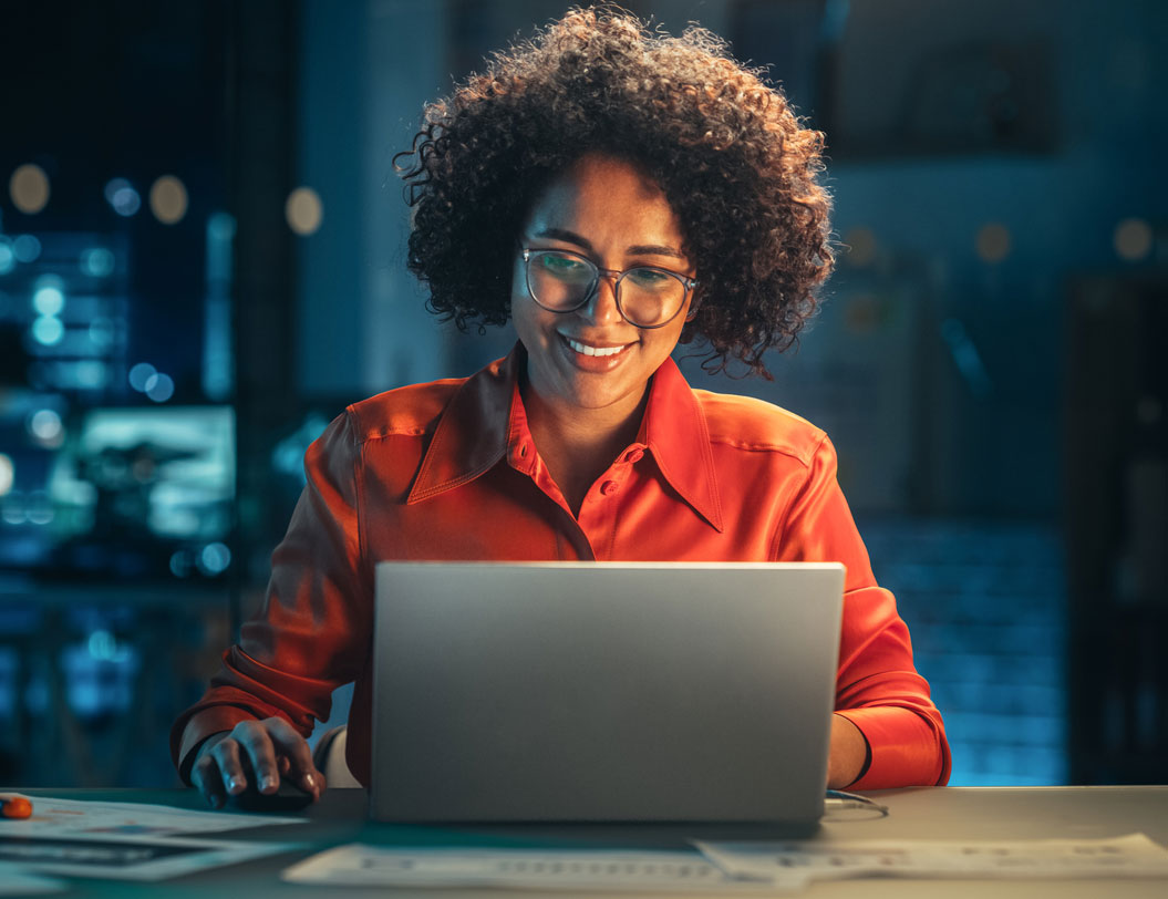 Woman smiling working on laptop at night