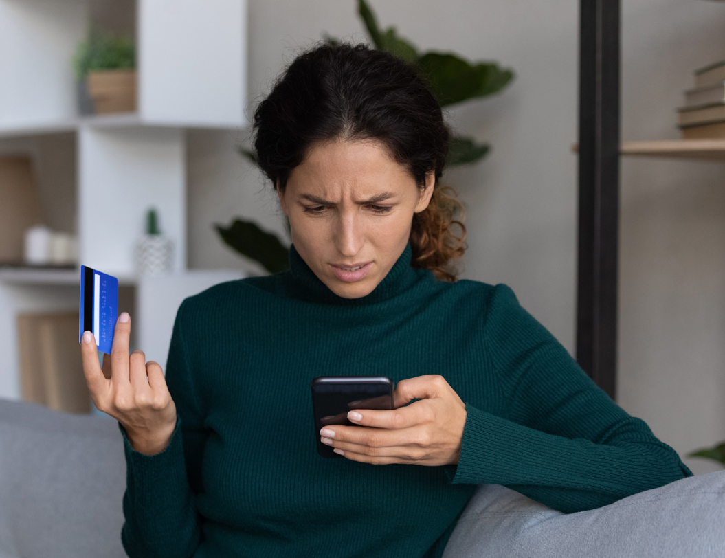 Confused woman holding cell phone and credit card