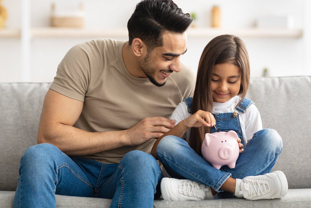 Father with daughter holding piggy bank