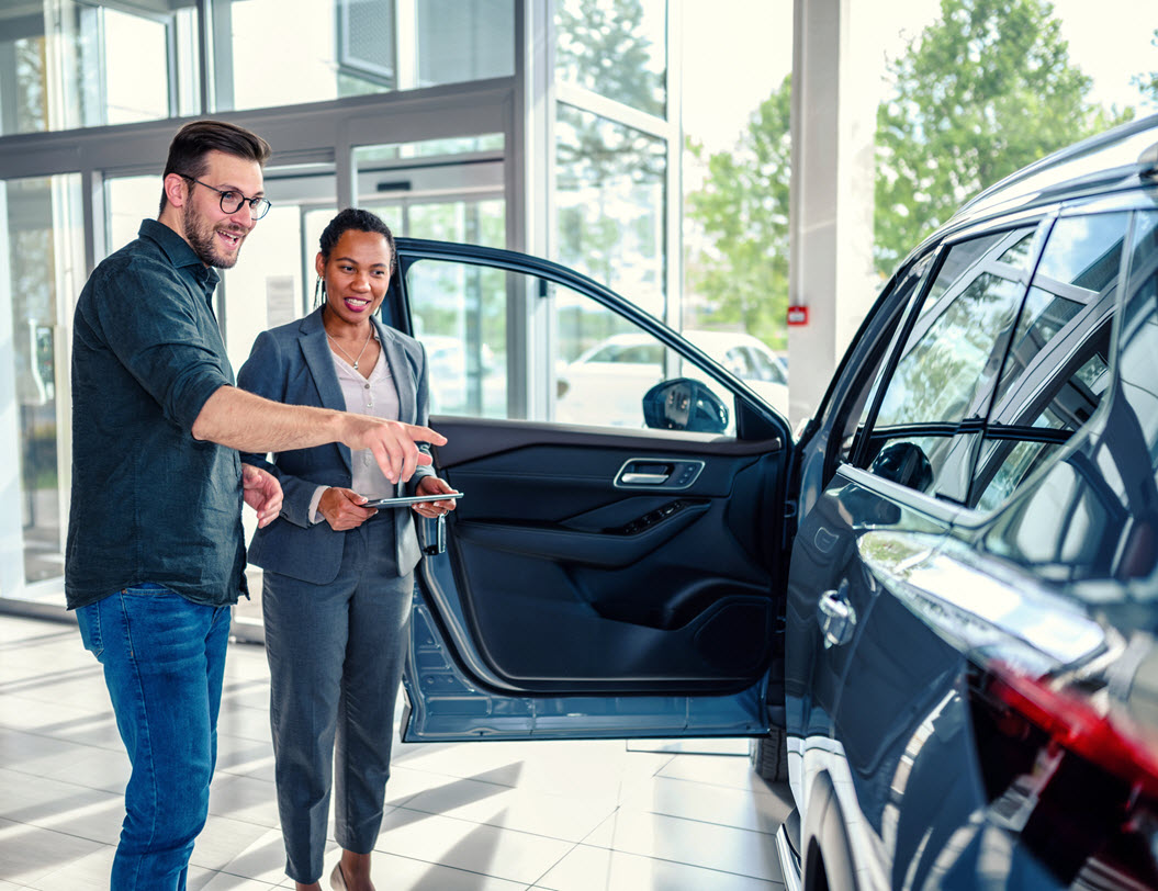 Female car sales person showing a car to male customer