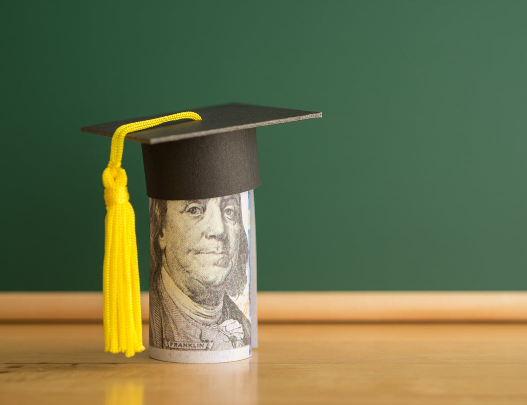 Rolled up 100 dollar bill with a graduation cap on top
