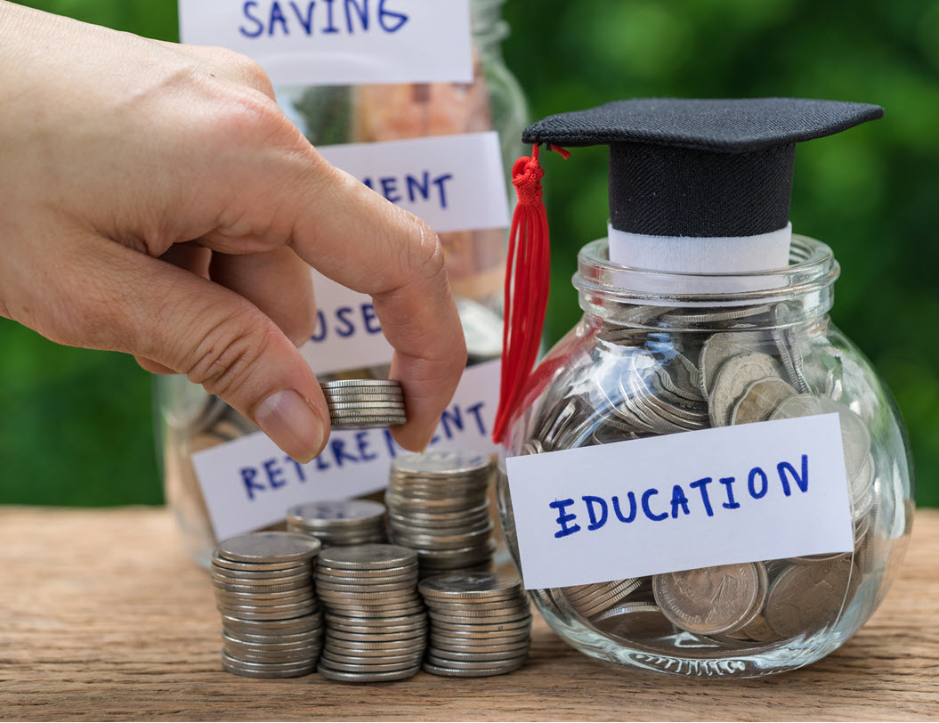 Hand stacking coins next to a jar of coins that says Education