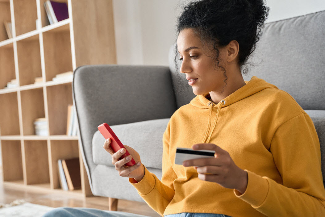 Woman using her phone and holding her credit card