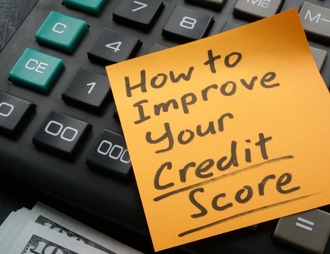Post it note on a computer keyboard that says How to Improve Your Credit Score