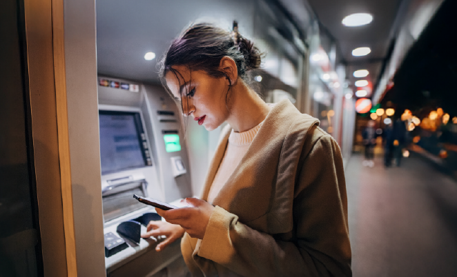 Young girl using an outdoor ATM