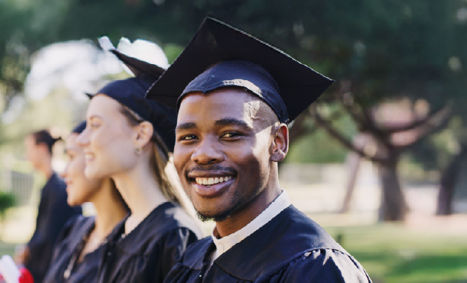 Young may college graduate in the foreground with other graduates in the background