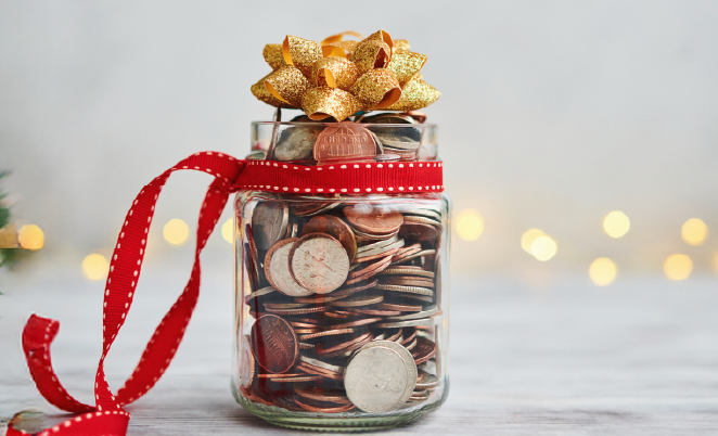 Glass jar of coins tied in a ribbon with a bow on top