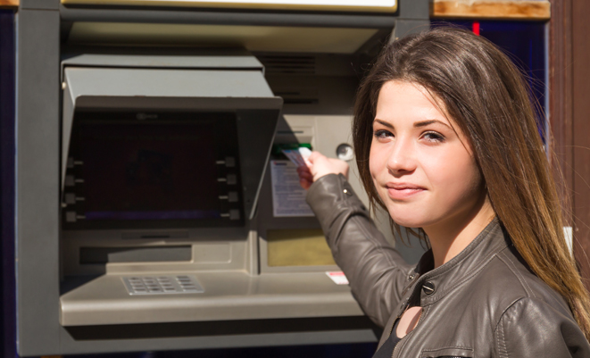 Young girl using an outdoor ATM