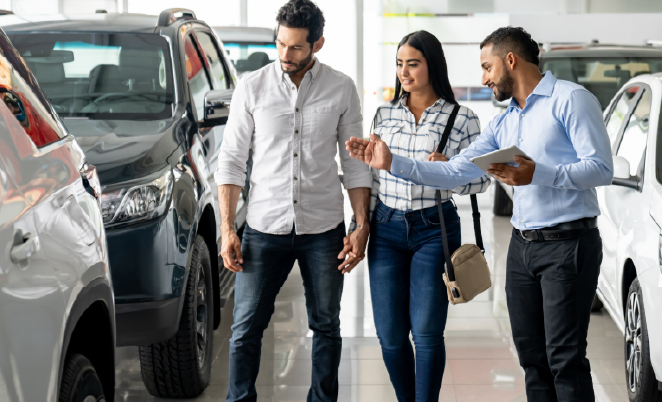 Man and woman speaking with a car dealer in the showroom