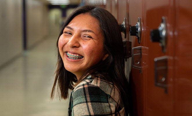 Young girl standing against a school locker
