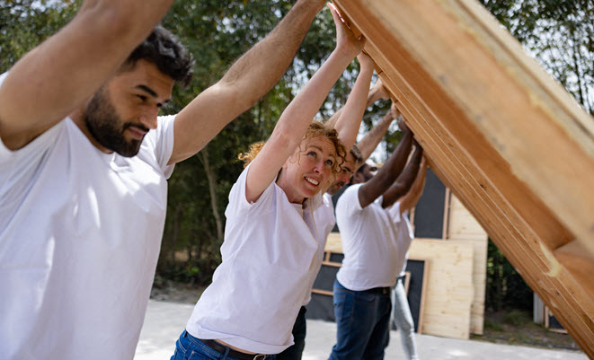 Five volunteers lifting a wall for a house