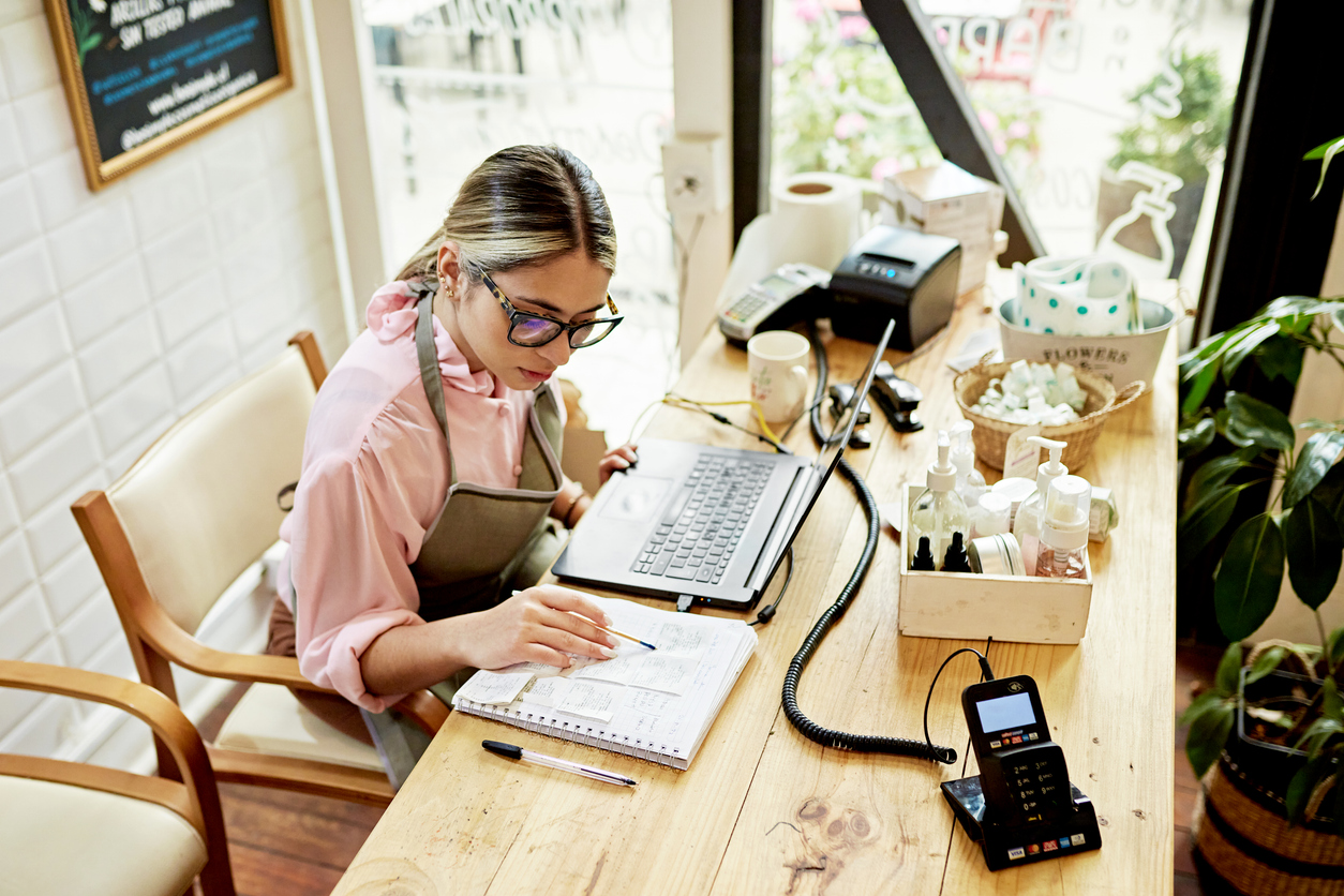Young business owner using laptop in retail shop stock photo
